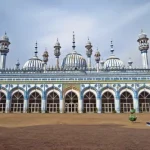 A mosque with blue and white decorative domes and arches, supported by Giving Hands.
