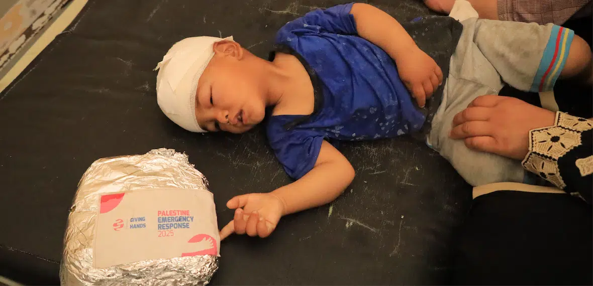 A child with a bandaged head lies on a couch next to an emergency food package labeled "Palestine Emergency Response 2025.