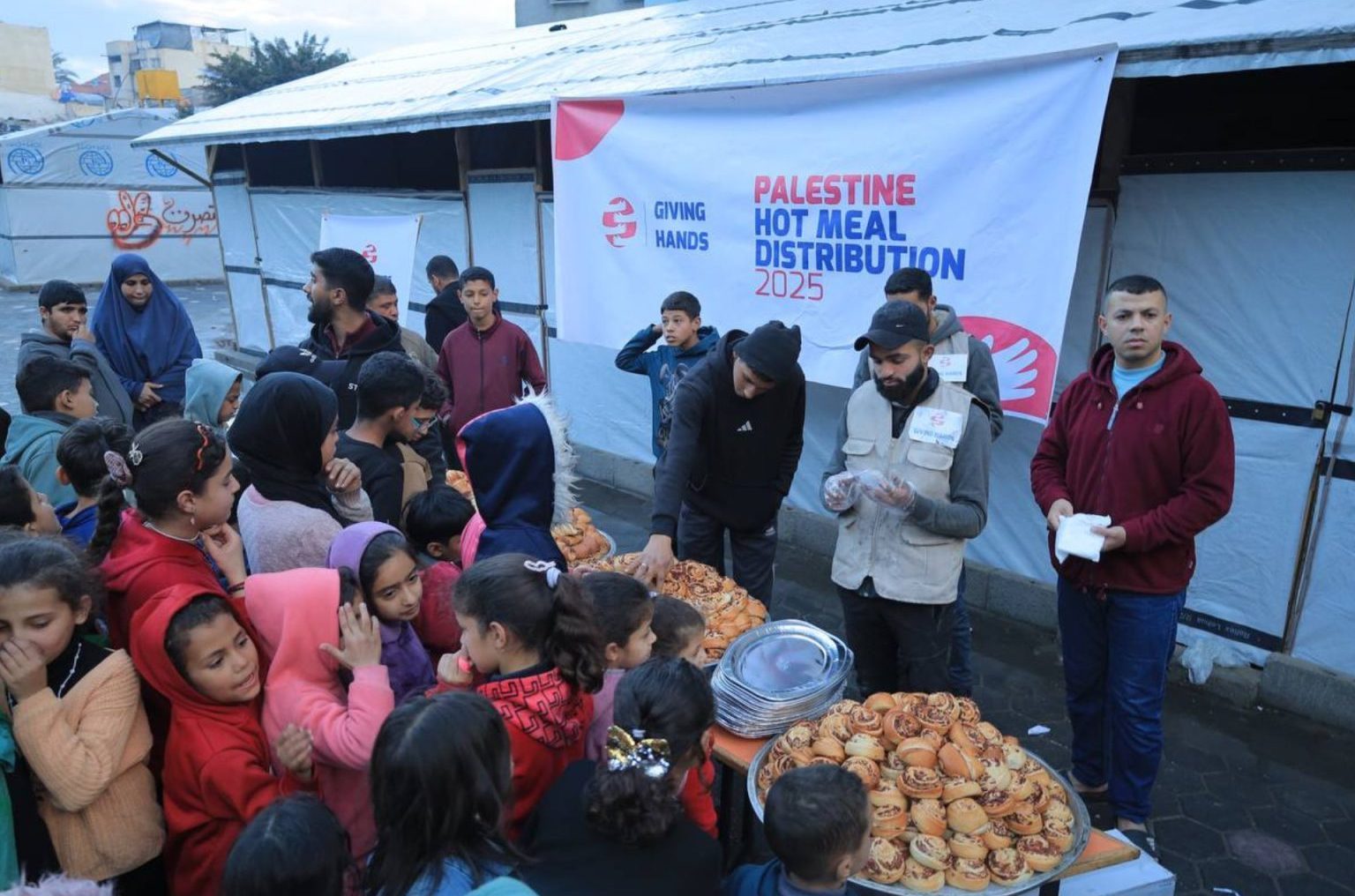 Crowd of children and families receiving hot meals during Palestine Hot Meal Distribution by Giving Hands Canada in 2025