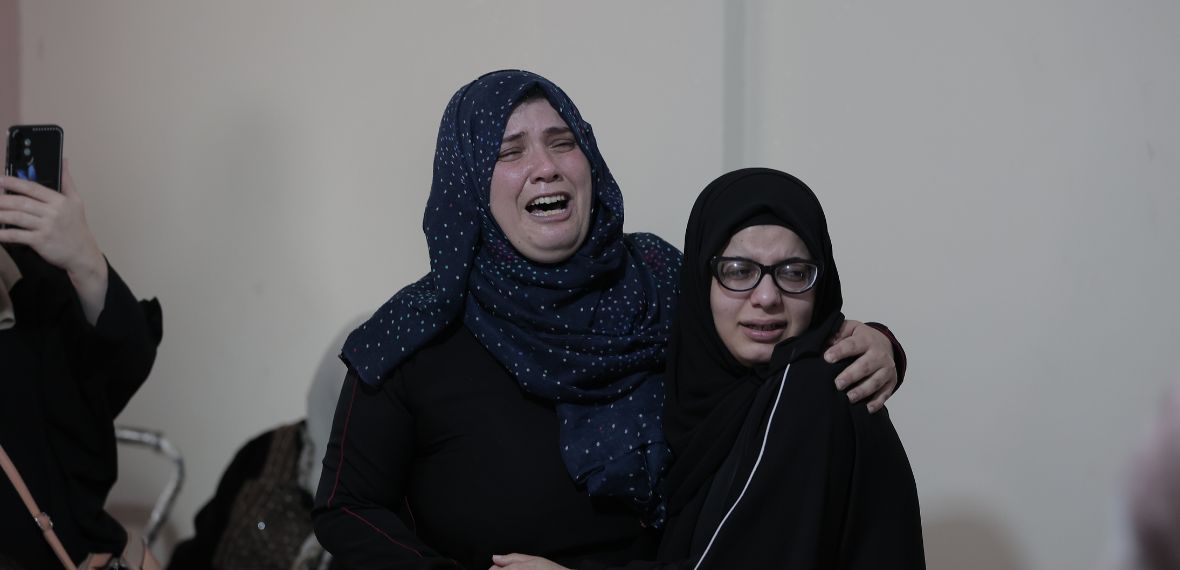 Two women in black attire stand together indoors, showing support during a Giving Hands event.