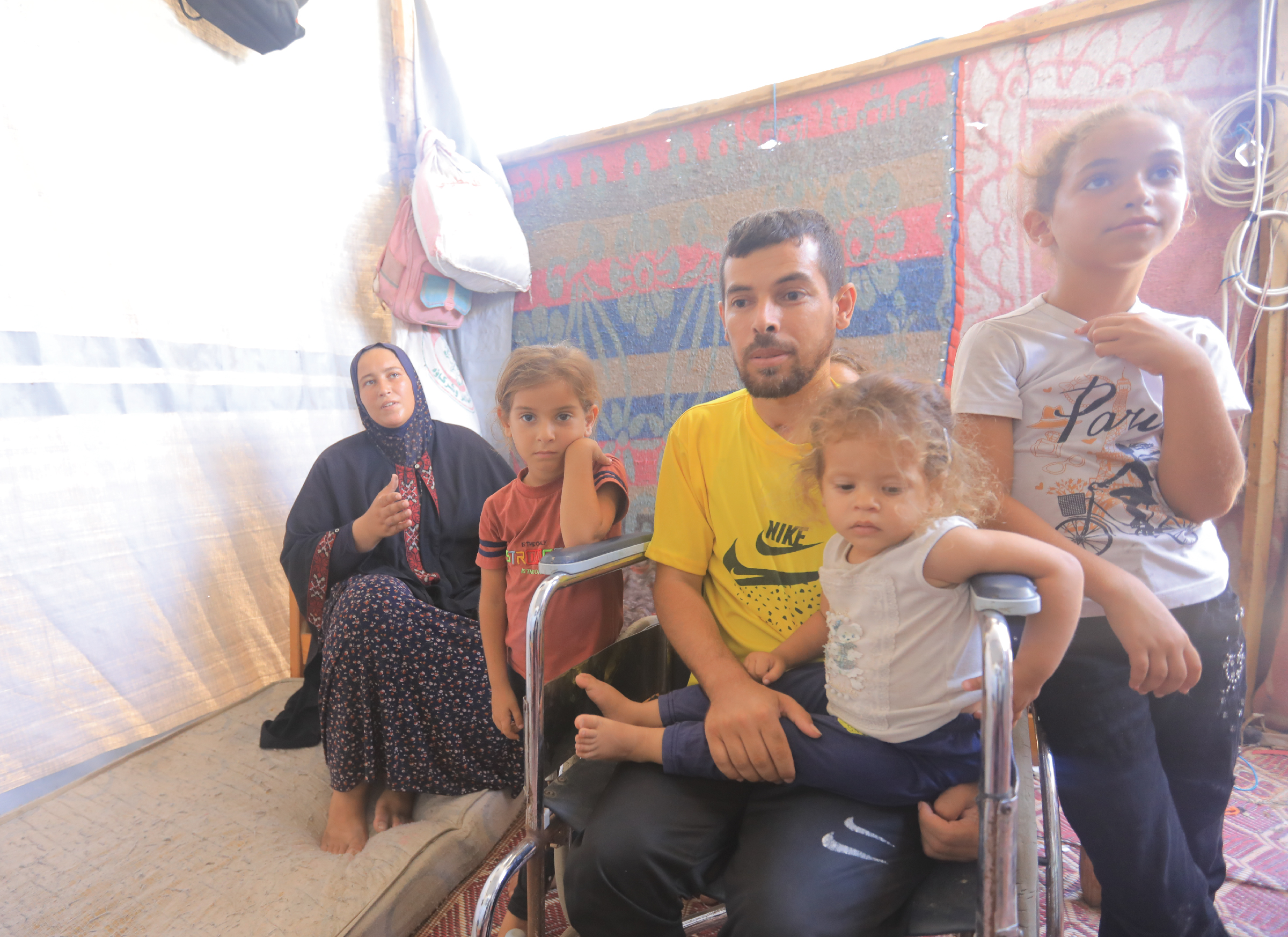 A family sitting together inside a tent, with children and adults gathered closely.