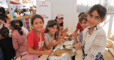 Children enjoying a meal together at a Giving Hands community event in Palestine