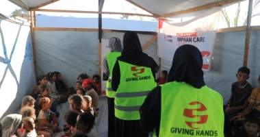 Giving Hands volunteers in safety vests leading a group activity for children at a Palestine Orphan Care event