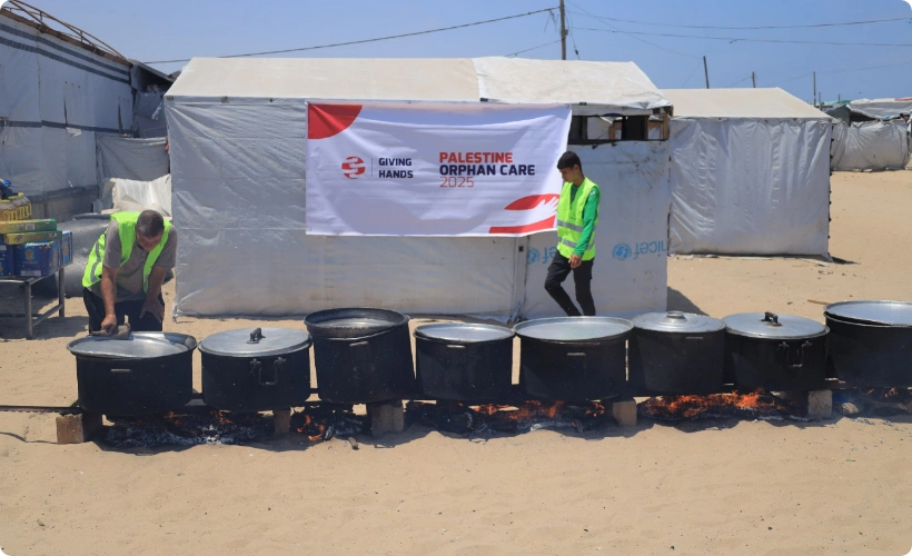 Giving Hands volunteers preparing large pots of food outdoors for Palestine Orphan Care program