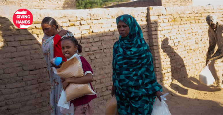 Families receiving food aid packages from Giving Hands charity, including staple supplies and essentials