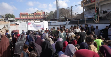 Large crowd gathered at a Giving Hands outdoor food distribution point