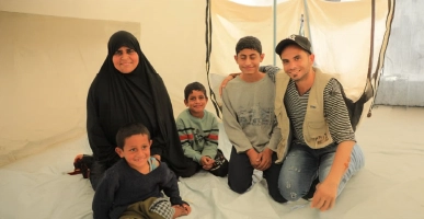 Family sitting together on the floor inside a relief tent